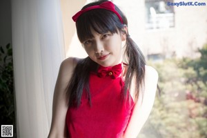 A woman in a red bikini posing by a window.