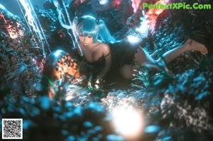 A woman with long blue hair sitting on the ground.