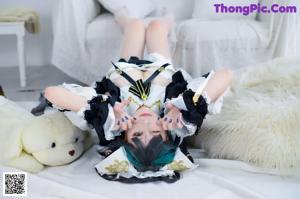 A woman in a maid outfit is laying on a bed.