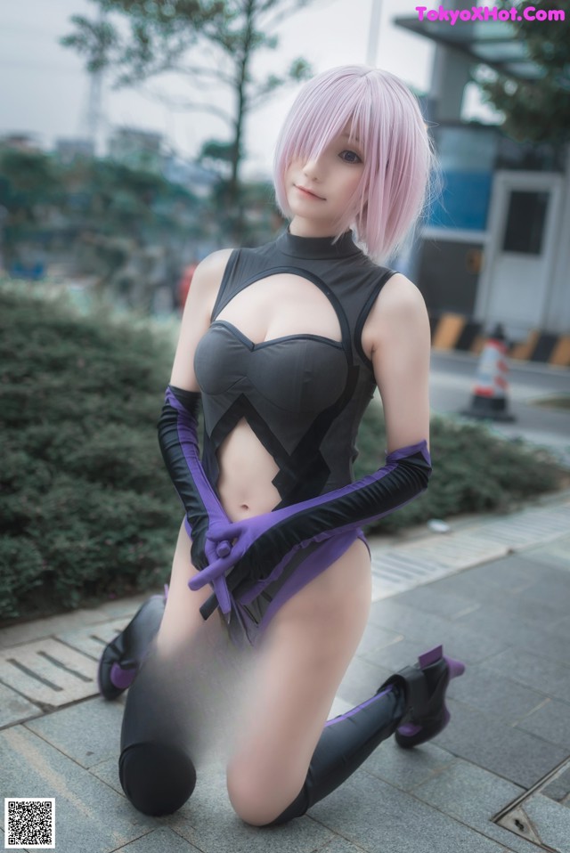 A woman in a black and purple outfit crouching down on the ground.