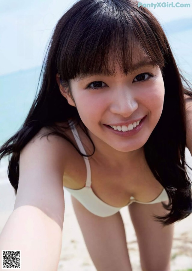 A woman in a white bikini taking a selfie on the beach.