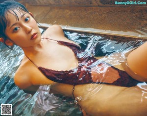 A woman in a blue tank top and pink panties posing in a bathroom.