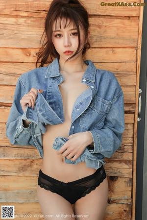 a woman in a denim shirt and black shorts posing for a picture