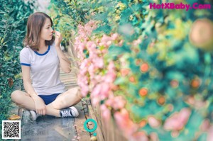 A woman sitting on a wooden bench in a garden.