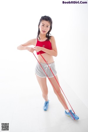 A woman in a red top and gray shorts posing for a picture.