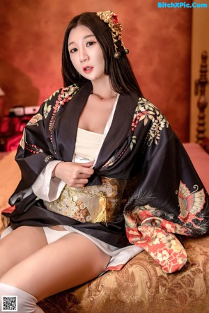 A woman in a white lingerie sitting on a bed.