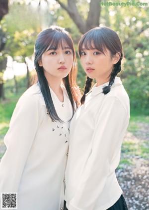 A couple of girls standing next to each other on a sidewalk.