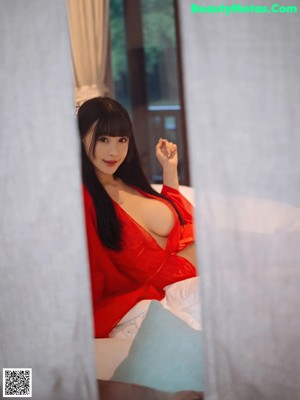 A woman in a red robe sitting on a window sill.