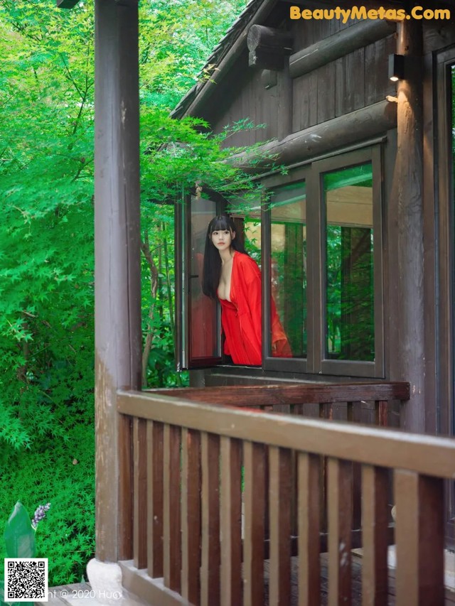 A woman in a red dress standing on a porch.