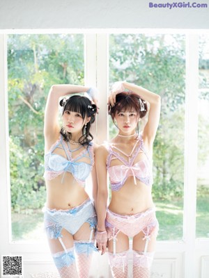 A couple of young women laying on top of a bed.