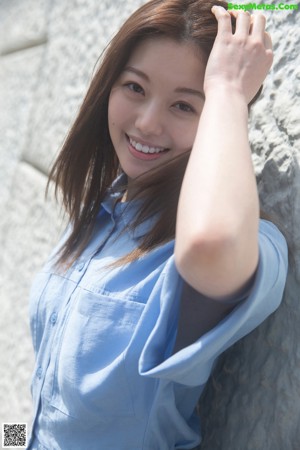 A woman in a blue and white bikini leaning against a wall.