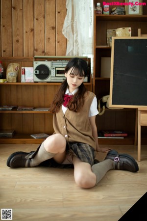 A naked asian woman sitting on the floor in a school uniform.