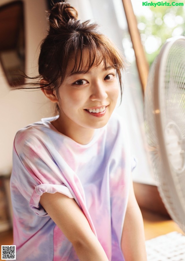 A young woman sitting in front of a fan.