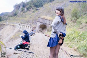 A woman in a blue skirt is sitting on a train track.