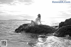 A woman in a bikini sitting on the edge of a swimming pool.