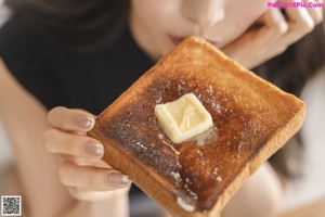 A woman sitting at a table with a plate of toast and a laptop.