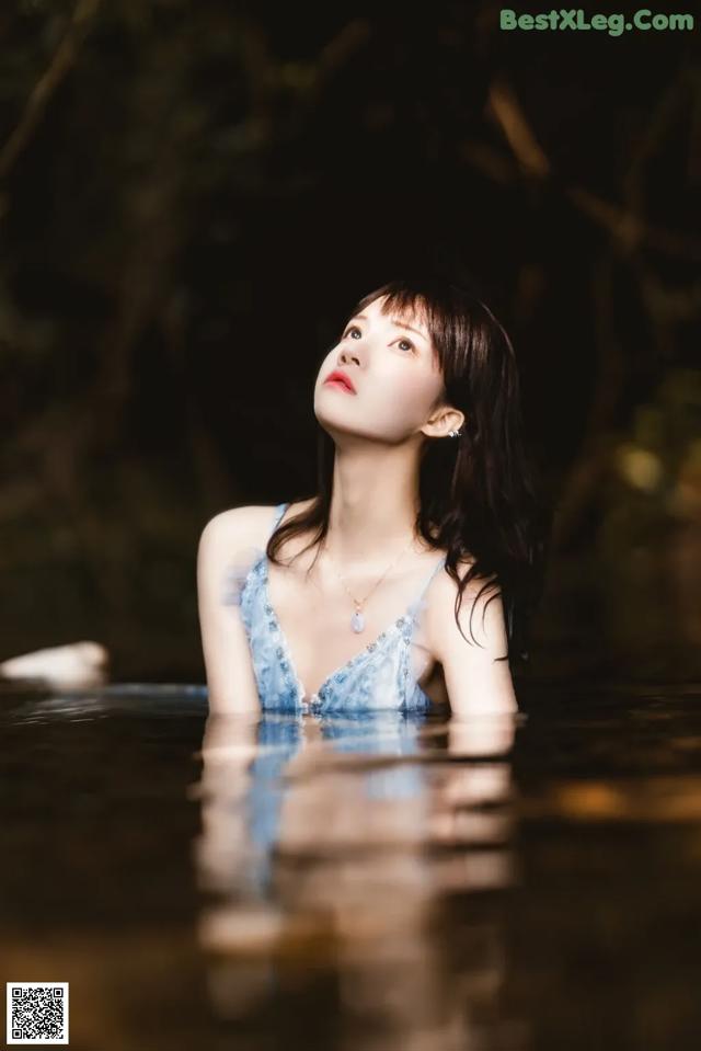 A woman in a blue dress is floating in the water.