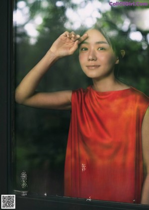 A woman sitting in front of a window looking out the window.