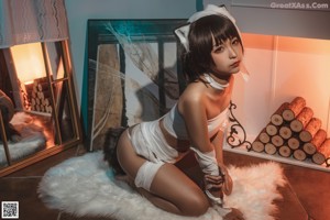 A woman in a white cat costume sitting on a white rug.