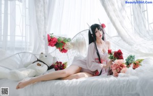 A woman sitting on a bed holding a bouquet of flowers.