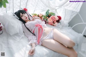 A woman in a white dress sitting on a bed.