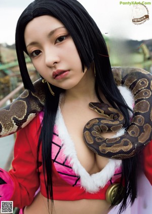 A woman holding a large snake in her arms.