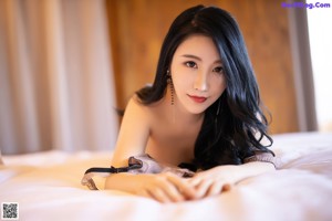 A woman in lingerie posing on a bed in a hotel room.