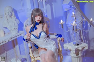 A woman in a white and blue lingerie sitting on a chair.