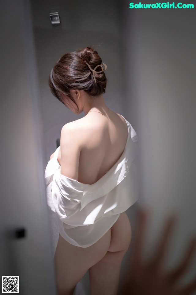 A woman in a white dress standing in a bathroom.