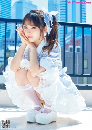 A young girl in a blue dress sitting on the floor.