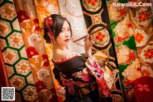 A woman in a kimono holding an umbrella on a city street.