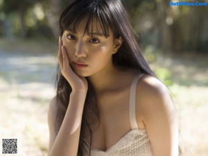 A woman sitting on the ground in a white dress.