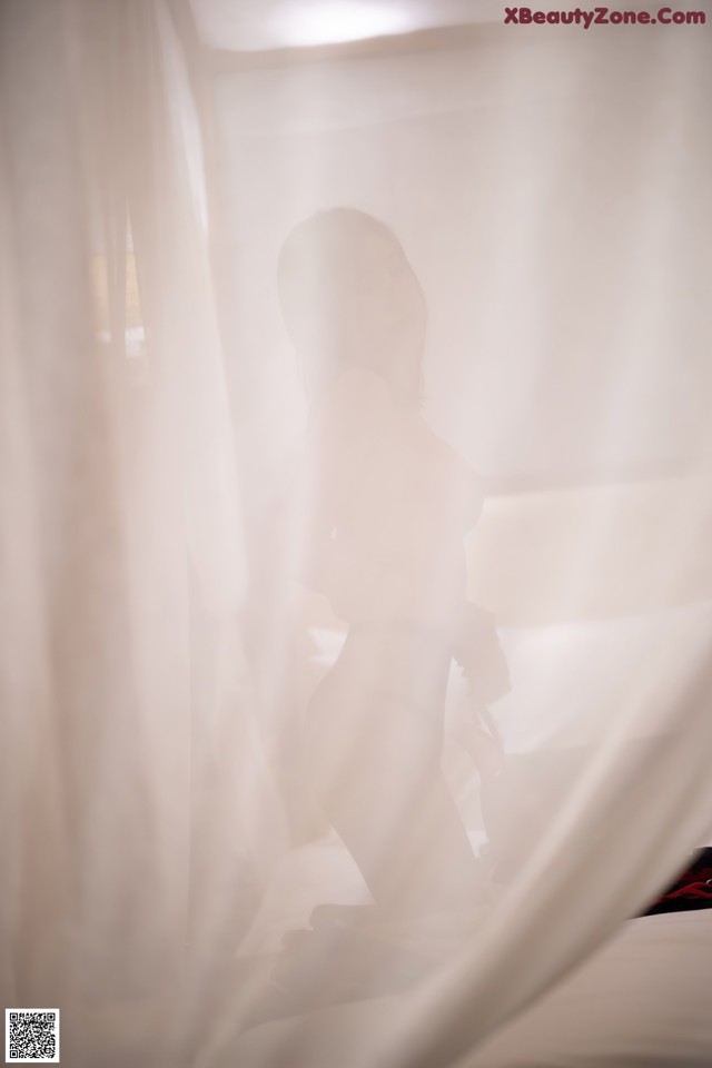 A woman standing in front of a white curtain.