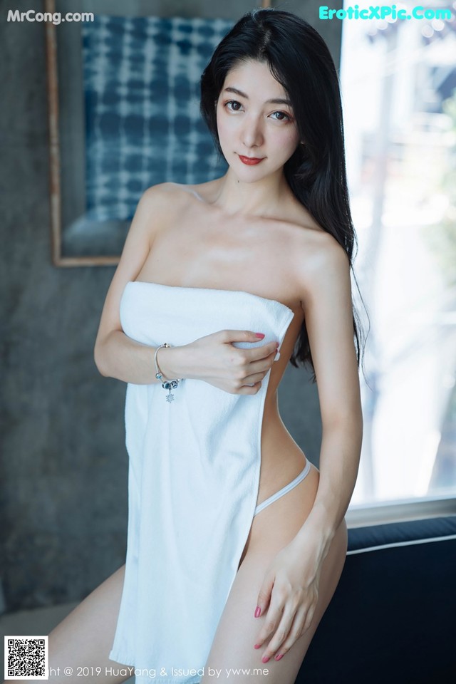 A woman in a white towel posing for a picture.