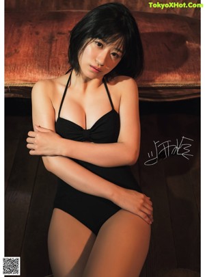 A woman in a black bathing suit laying on a couch.