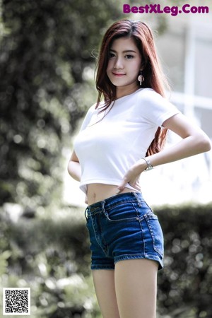 A woman in a white shirt and blue shorts standing on a balcony.