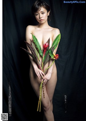 A naked woman holding a bunch of flowers in her hands.