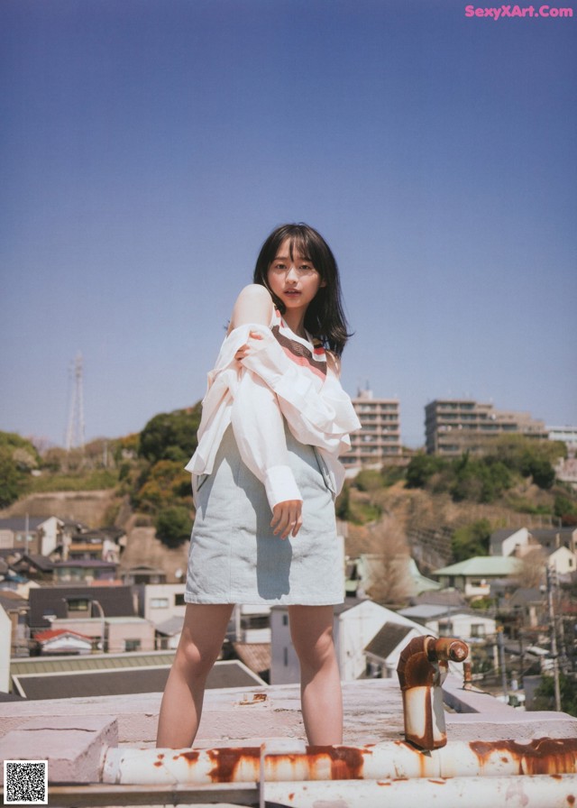 A woman standing on top of a roof next to a fire hydrant.