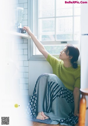 A young woman leaning against a wall with her hand on her chin.
