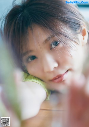 A woman sitting in front of a window wearing a white shirt.