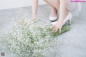 A woman in a white dress holding a bunch of flowers.