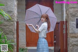 A woman sitting on the ground holding an umbrella.