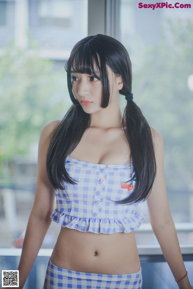 A woman in a blue and white checkered top posing for a picture.